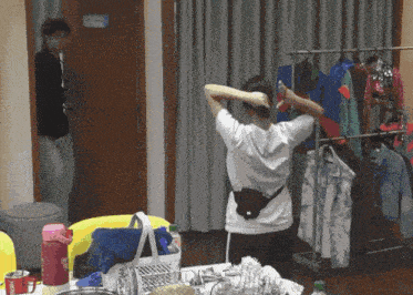 a woman adjusts her hair in a room with a sign that says ' dressing room '