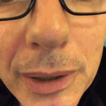 a close up of a man 's face with glasses on