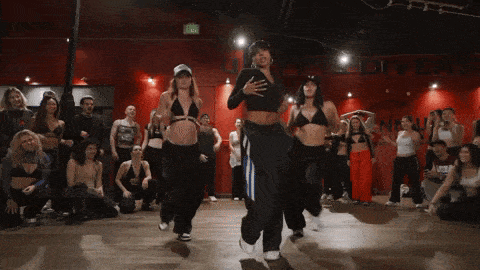a group of women are dancing in front of a red wall with the word exit on it
