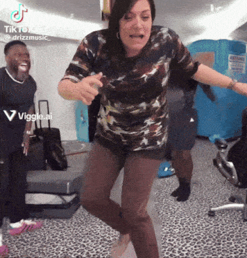 a woman in a camouflage shirt is dancing with a man in a black shirt