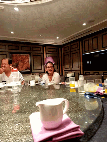 a woman sitting at a table with a pink napkin and a white cup