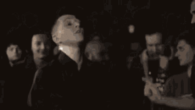 a group of young men are standing in a crowd .