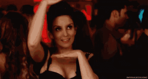 a woman in a black dress is smiling while dancing in a club .