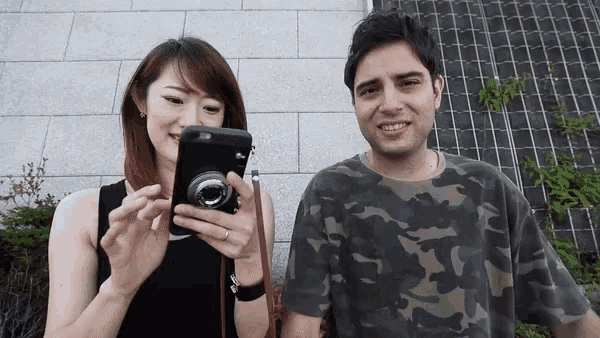 a man and a woman are looking at a camera together
