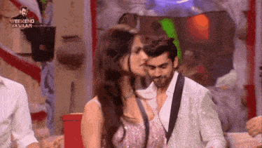 a man and a woman are kissing on a stage in front of a sign that says weekend ka vaar