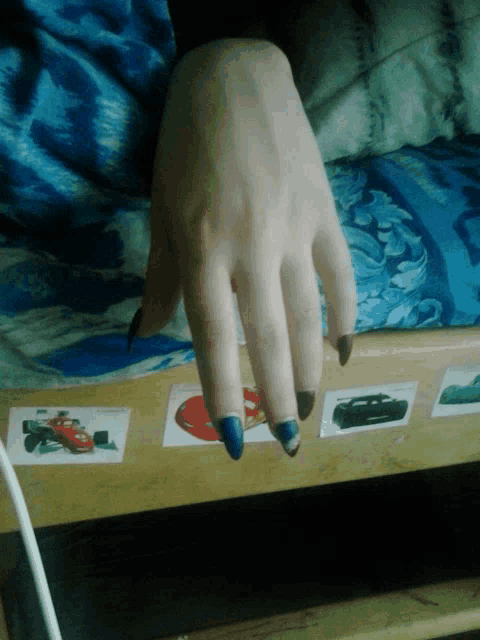 a person 's hand rests on a wooden bed with stickers of cars on it