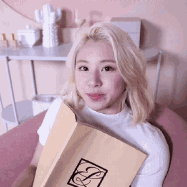 a woman with blonde hair is holding a book with a letter s on it