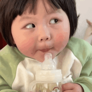 a little girl is drinking from a bottle with a straw .