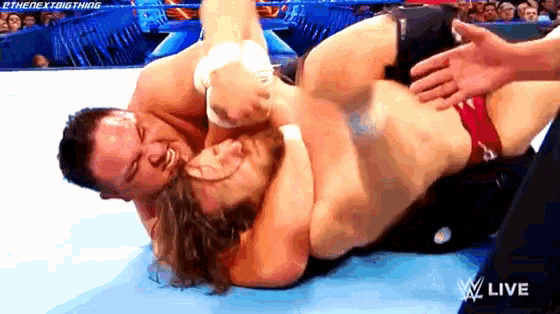 two men are wrestling in a wrestling ring with the words w live on the bottom right corner .