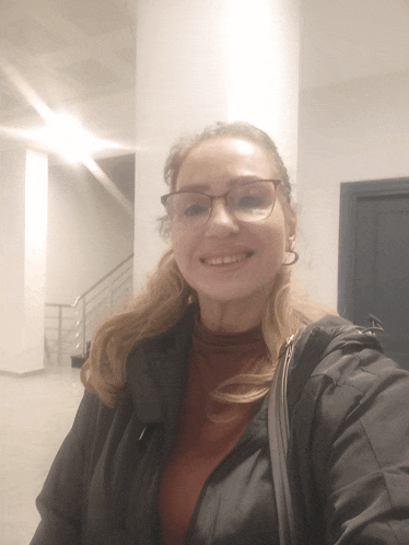 a woman wearing glasses and a black jacket smiles