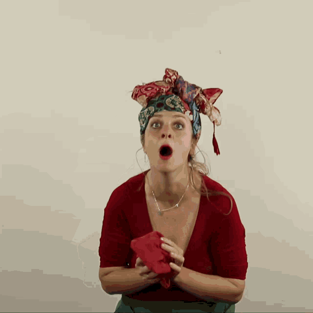 a woman with a scarf on her head holds a red cloth in her hands