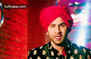 a man wearing a red turban and a black suit .