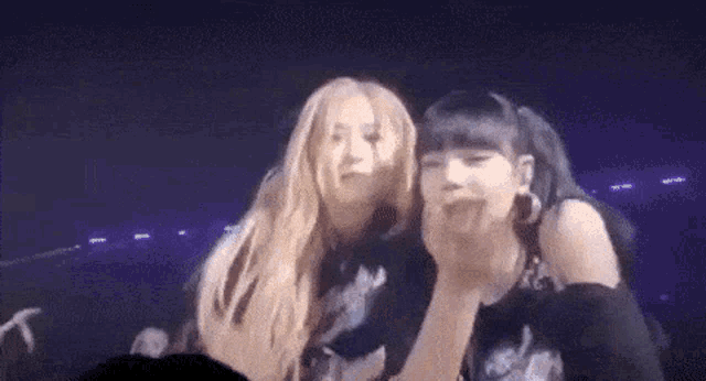 two women are standing next to each other on a stage and looking at each other .