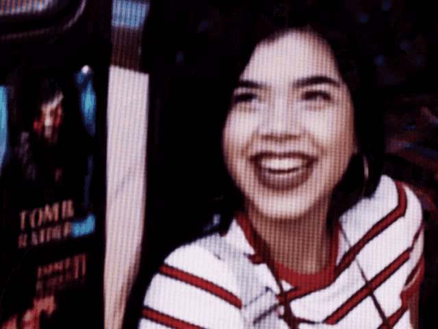 a woman is smiling in front of a tomb raider advertisement