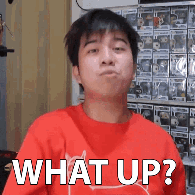 a man in a red shirt is making a funny face and says what up