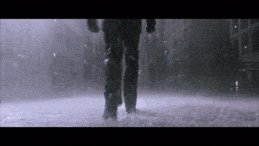a person is walking through a puddle of water in the rain .