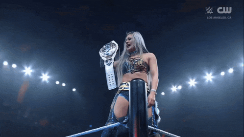 a woman is holding a wrestling championship belt over her head