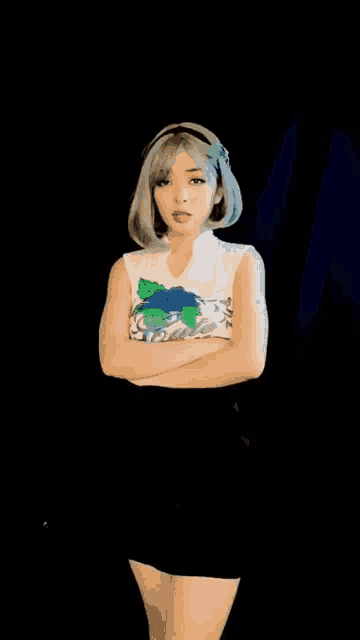 a woman is standing with her arms crossed and wearing a white shirt with a map of the world on it .