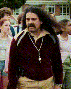 a man with long hair and a mustache is walking in a crowd of people