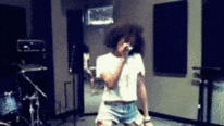 a woman singing into a microphone in a dark room