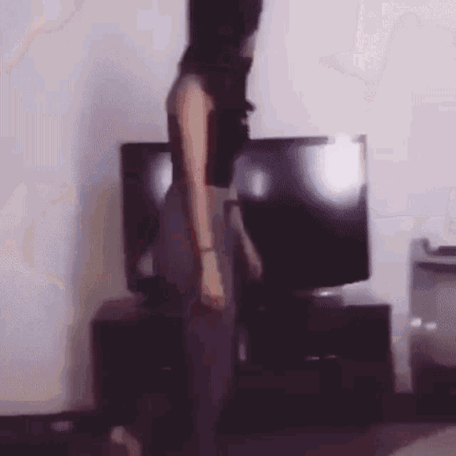 a woman is dancing in a living room in front of a television .