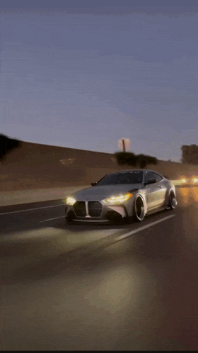 a silver car is driving down a highway at night