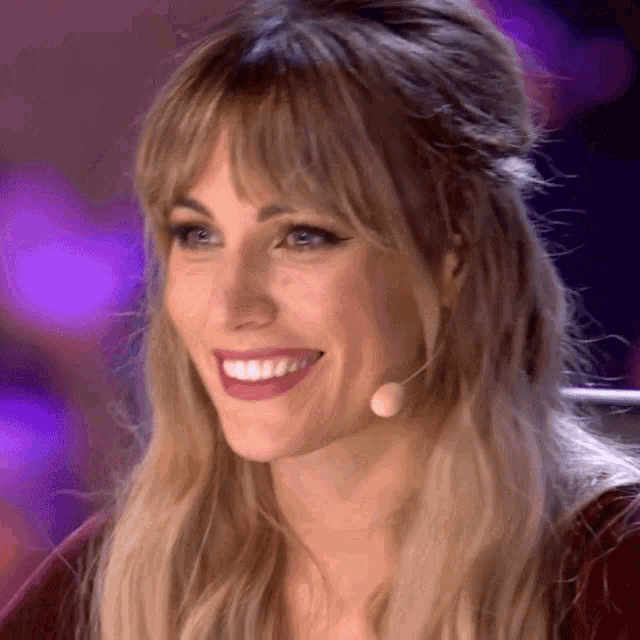 a woman with a microphone in her hair is smiling