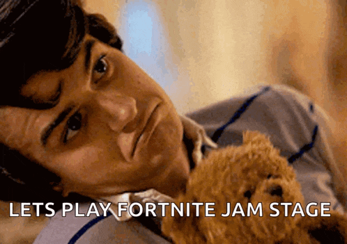 a man laying down holding a teddy bear with the words lets play fortnite jam stage written below him