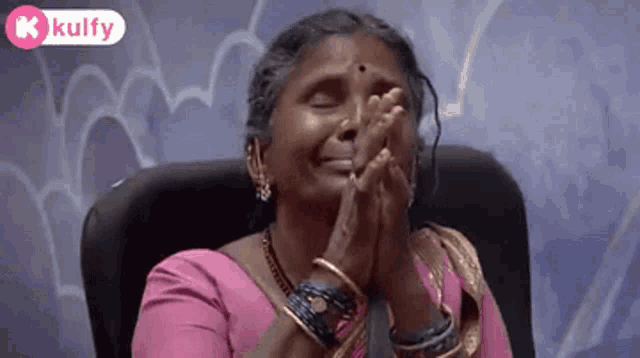 a woman is sitting in a chair with her eyes closed and her hands folded .