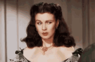 a close up of a woman wearing a necklace and a green dress