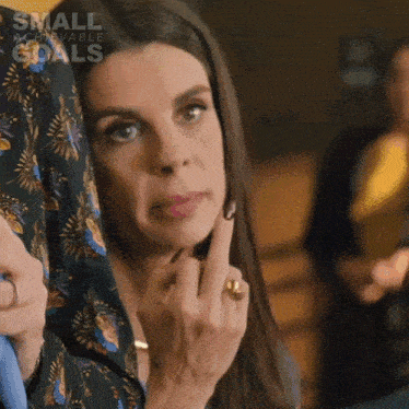 a woman with a ring on her finger is holding her finger to her face .