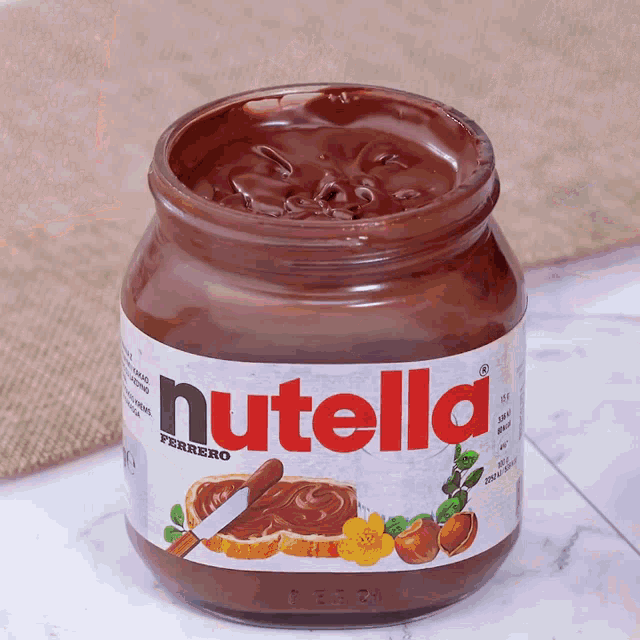 a jar of nutella sits on a table with a knife in it