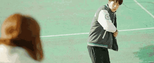 a man and a woman are standing on a tennis court . the man is pointing at the woman .