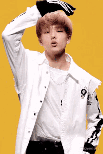 a young man wearing a white jacket and a white t-shirt is making a face