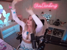 a woman is sitting in a chair with her arms in the air in front of a microphone .