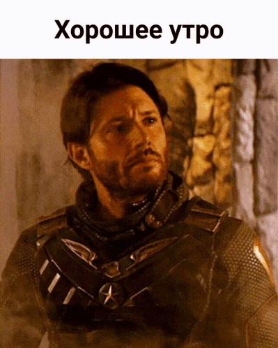 a man with a beard is standing in front of a stone wall with the words хорошее утро written above him