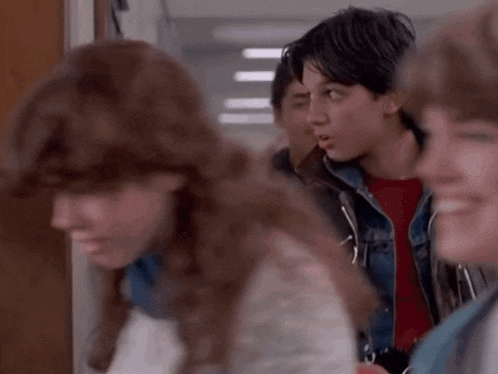 a group of people are standing in a hallway and one of them is wearing a red shirt