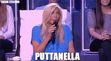 a woman in a blue shirt is speaking into a microphone and the word puttanella is on the screen