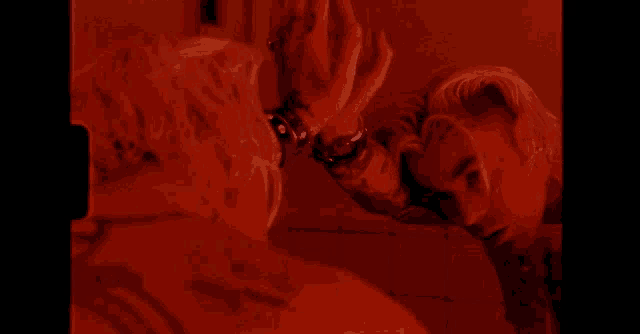 a man looking at his reflection in a mirror in a red room