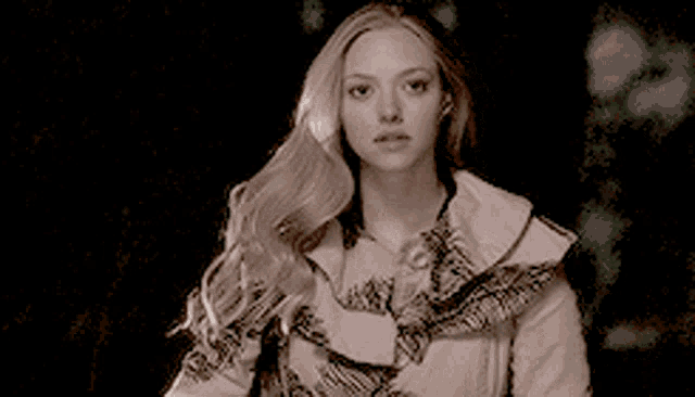 a woman with long blonde hair is wearing a ruffled coat