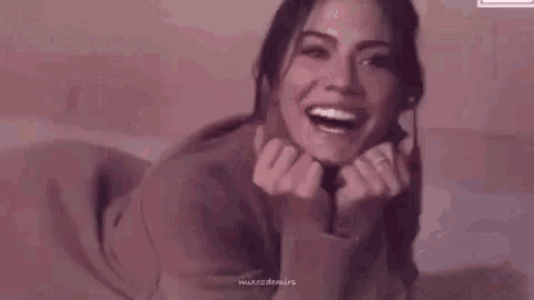 a woman is laying on a bed with her legs crossed and smiling .