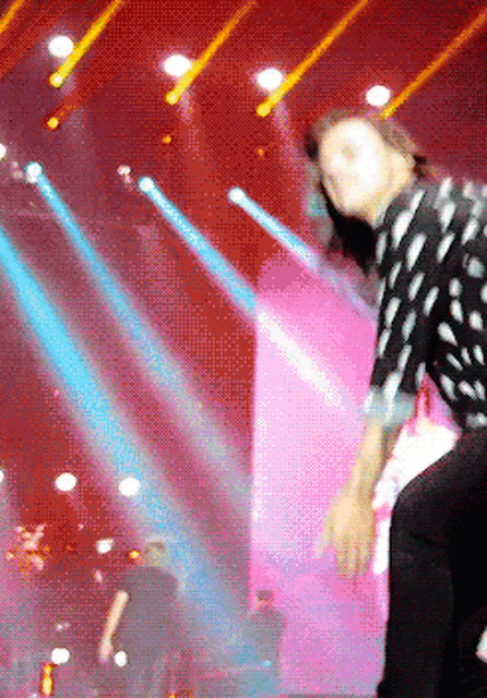 a man in a polka dot shirt stands on a stage
