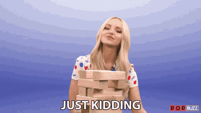 a woman is holding a stack of wooden blocks and the words just kidding are above her