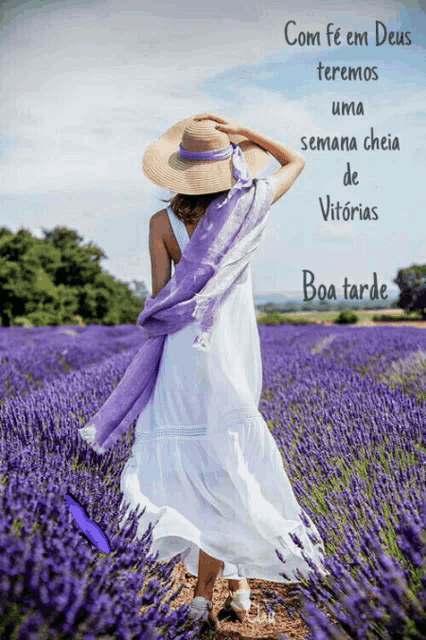 a woman in a white dress and straw hat is walking through a field of lavender