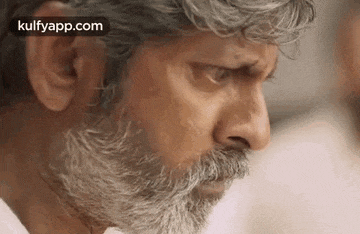 a close up of a man 's face with a beard and gray hair .