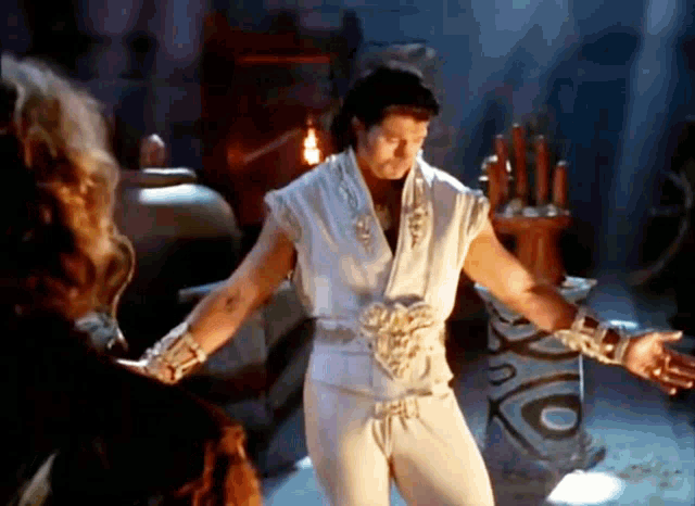 a man in a white shirt and white pants is standing in a room