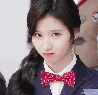 a close up of a woman wearing a bow tie and a school uniform .