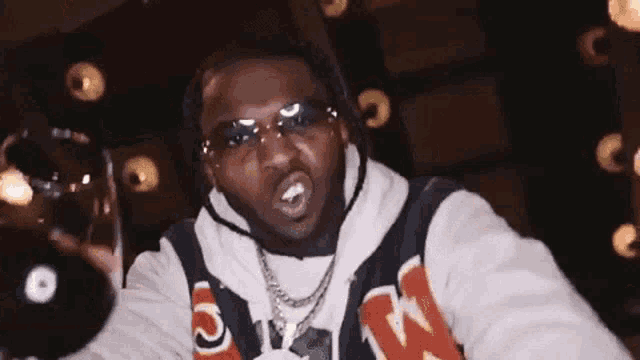 a man wearing sunglasses and a hoodie is giving a middle finger .