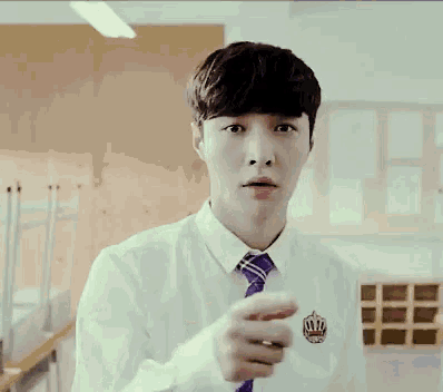 a man in a white shirt and purple tie is pointing at the camera