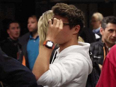 a man wearing glasses and a watch covering his face